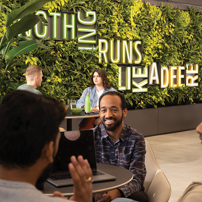 Some of Deere's diverse Chicago employees relax in a lounge with a sign that reads "Nothing Runs Like a Deere" behind them