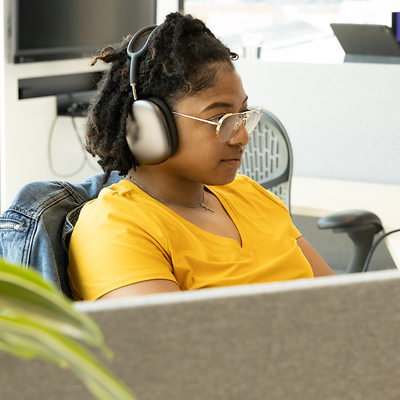 A recent graduate listens to music while she works at her desk