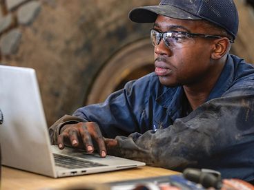 A John Deere service technician working on a laptop.