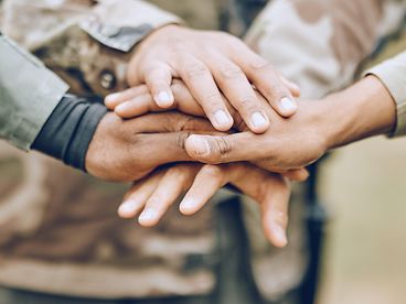A group of soldiers place their hands together in a circle