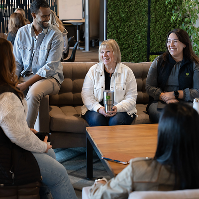 A group of coworkers laughing as they take a break in a room filled with plants