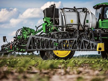 Closeup view of a John Deere sprayer boom in an open field. 