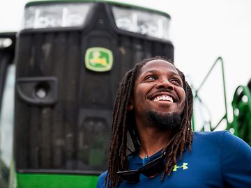 Smiling person standing in front of John Deere agriculture equipment.