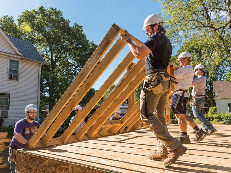 Habitat for Humanity volunteers lifting a framed wall.