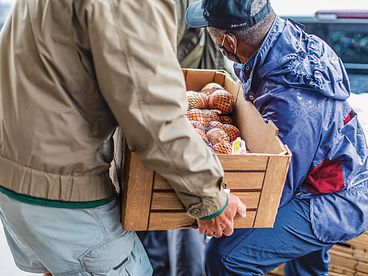 Volunteer carrying a box of vegetables.