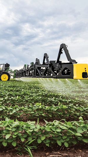 Closeup view of a John Deere sprayer boom in an open field. 